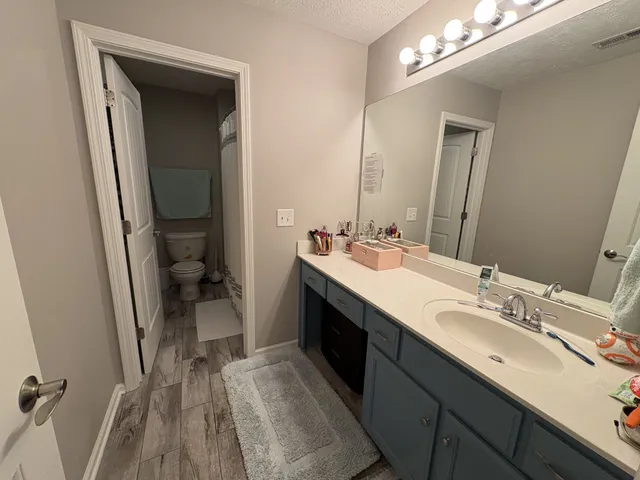 a en suite bathroom with a double vanity sink a toilet and a mirror