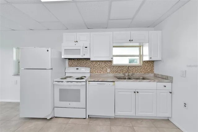 a kitchen with white cabinets and white appliances