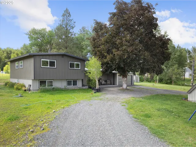 a front view of a house with garden and trees