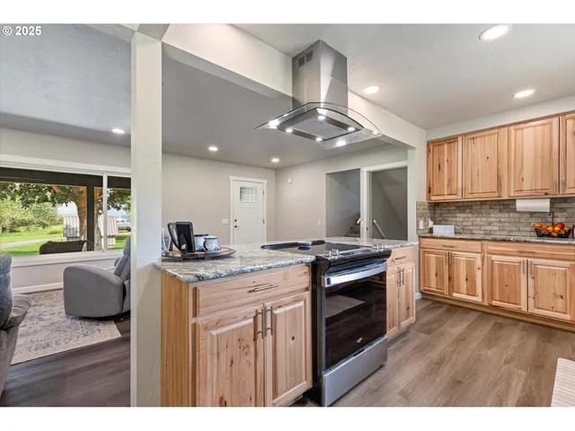 a kitchen with stainless steel appliances granite countertop a stove top oven a sink dishwasher and white cabinets with wooden floor