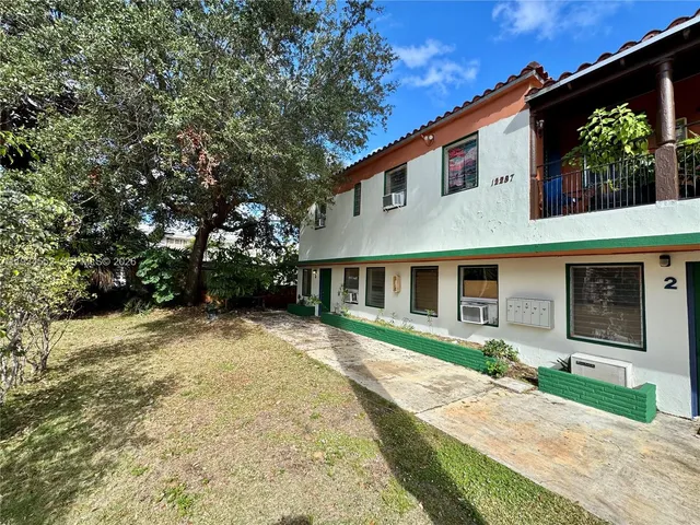 a front view of a house with a yard and potted plants