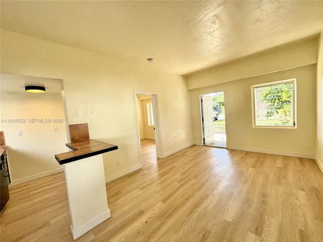 a view of a livingroom with wooden floor and a bathroom