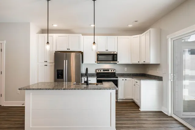 a kitchen with stainless steel appliances granite countertop a refrigerator a stove a sink and white cabinets