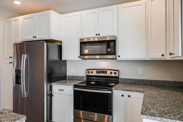 a kitchen with stainless steel appliances granite countertop a stove a refrigerator and a microwave