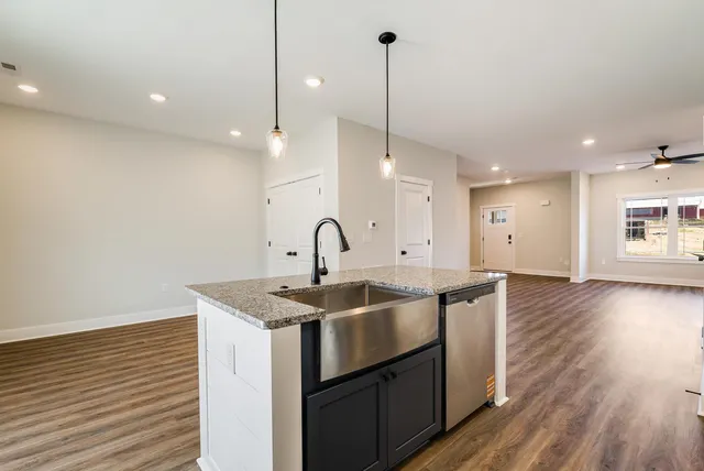 a kitchen with stainless steel appliances granite countertop a sink a window and wooden floor