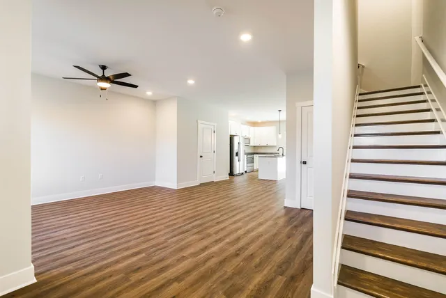 a view of a hallway with wooden floor and a ceiling fan