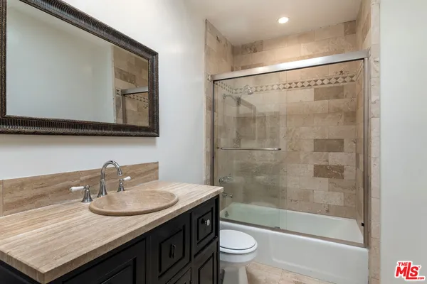 a bathroom with a granite countertop sink a toilet and shower
