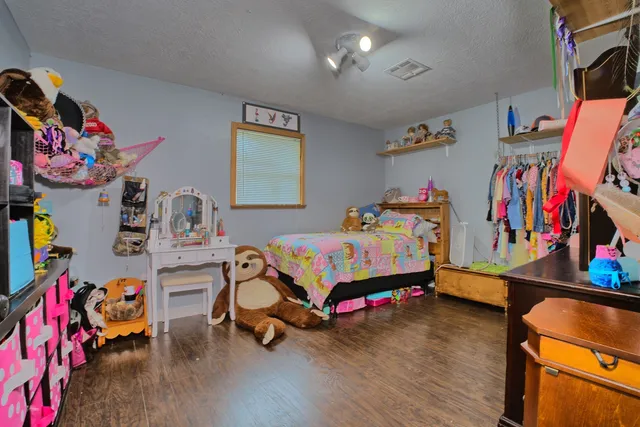 a bedroom with a bed a dresser and potted plant