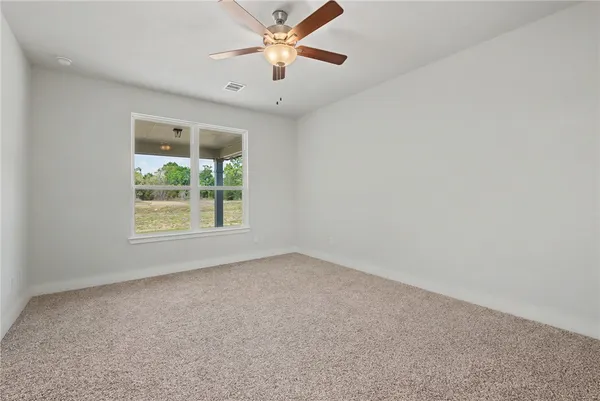 an empty room with a window and a fan