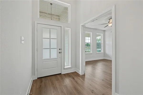 an empty room with wooden floor fan and windows