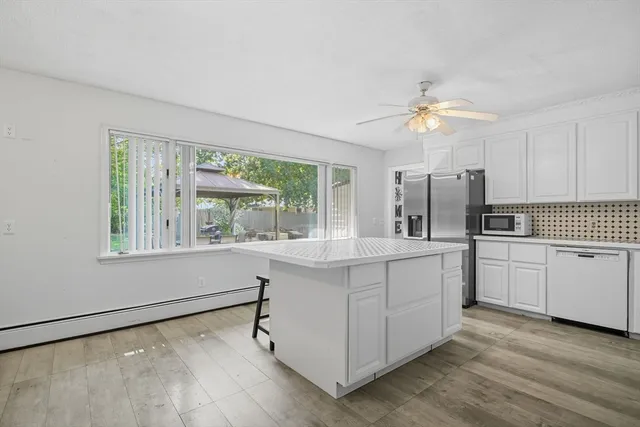 a view of kitchen with kitchen island a large window cabinets and stainless steel appliances