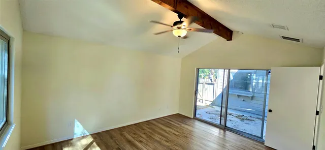 an empty room with wooden floor fan and windows