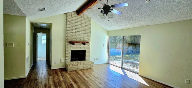 a view of a livingroom with wooden floor a ceiling fan and a window