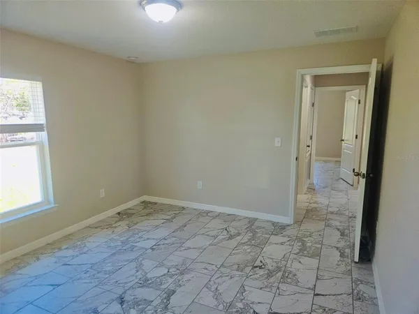 a view of an empty room with window and bathroom
