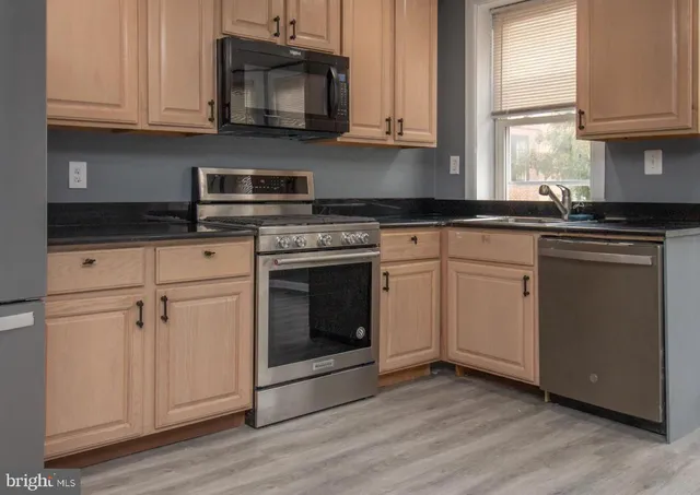 a kitchen with granite countertop white cabinets stainless steel appliances and a sink