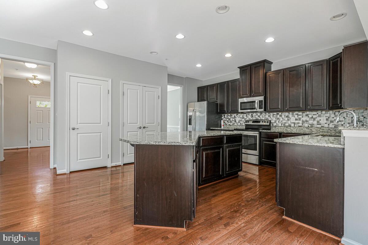 6911 Simmons Lane Clinton, MD 20735 - Photo 11 of 41 a kitchen with kitchen island granite countertop wooden cabinets and stainless steel appliances
