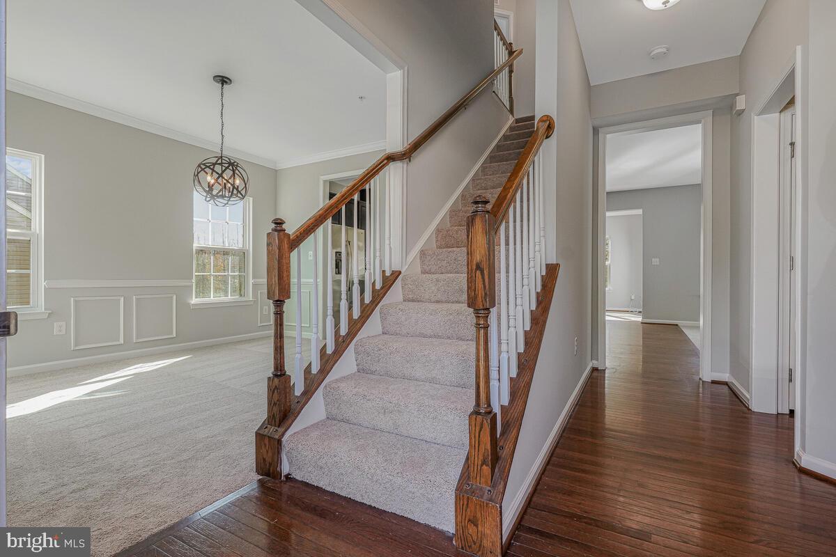 6911 Simmons Lane Clinton, MD 20735 - Photo 4 of 41 a view of staircase with wooden floor and a chandelier
