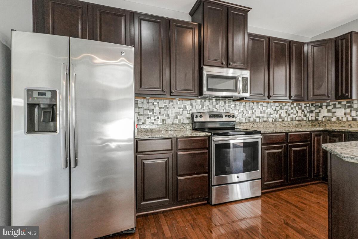 6911 Simmons Lane Clinton, MD 20735 - Photo 9 of 41 a kitchen with kitchen island granite countertop stainless steel appliances and wooden cabinets