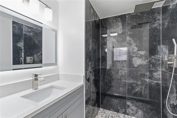 a bathroom with a shower sink and mirror