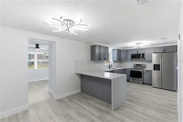 a large kitchen with cabinets wooden floor and stainless steel appliances