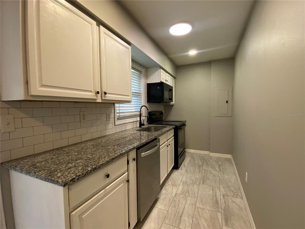 39656 Meadowood Loop Zephyrhills, FL 33542 - Photo 11 of 30 a kitchen with stainless steel appliances granite countertop a sink stove and microwave