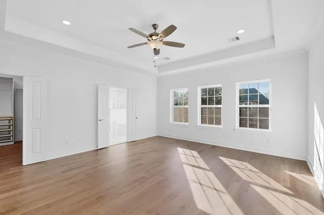 a view of empty room with wooden floor and ceiling fan