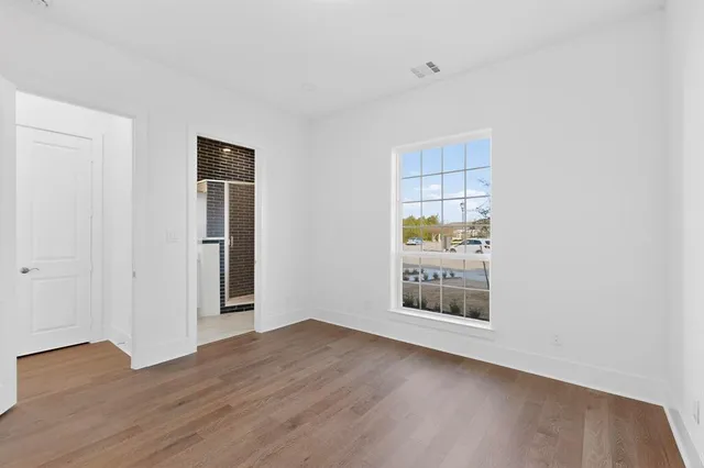 an empty room with wooden floor chandelier and windows