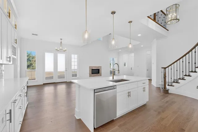 a kitchen with stainless steel appliances granite countertop a white stove top oven a sink and dishwasher with wooden floor