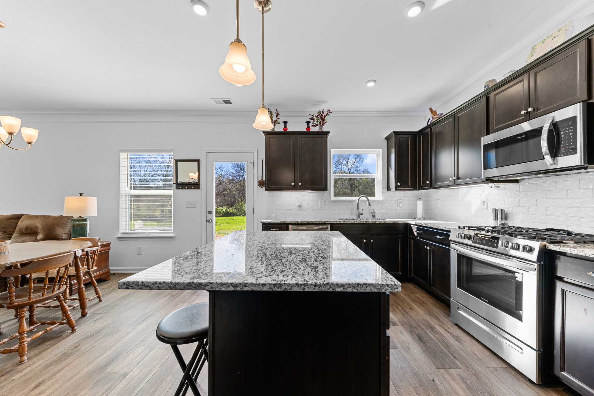 229 Stonewall Road Columbia, TN 38401 - Photo 18 of 61 a kitchen with stainless steel appliances granite countertop a stove top oven a sink a dining table and chairs with wooden floor