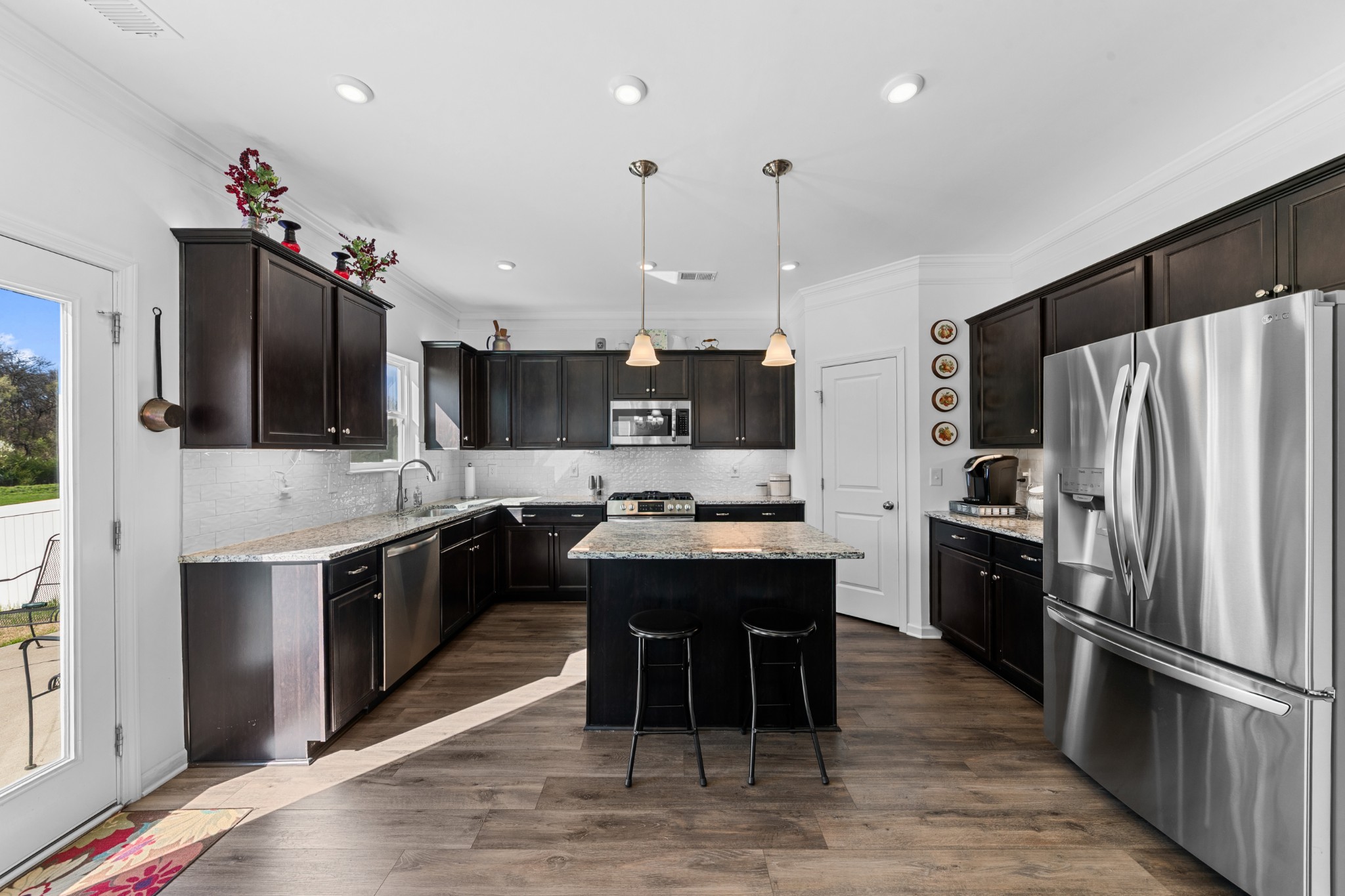 229 Stonewall Road Columbia, TN 38401 - Photo 5 of 61 a kitchen with stainless steel appliances kitchen island granite countertop a refrigerator a sink dishwasher a stove and a dining table with wooden floor