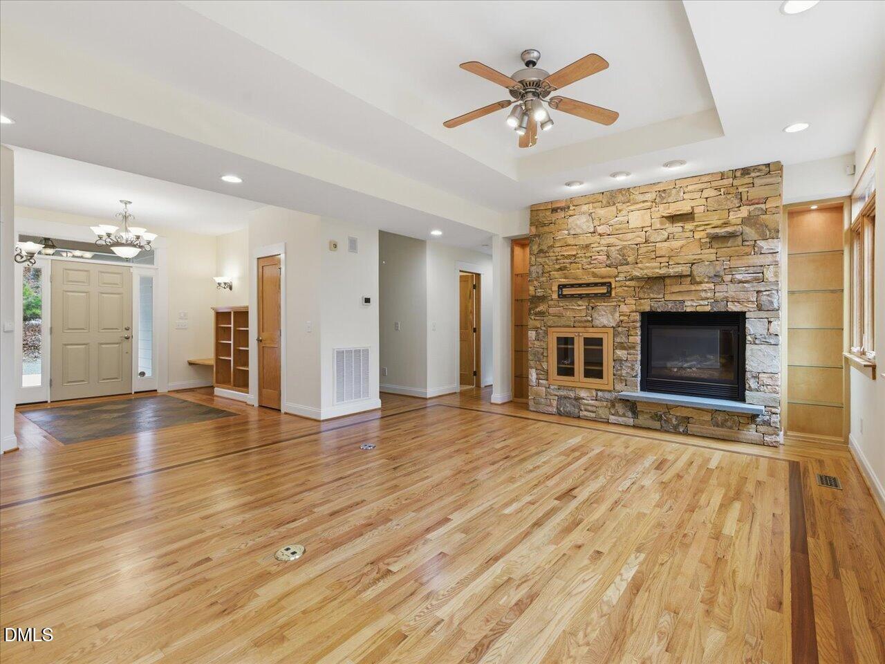 67 Bingham Ridge Drive Pittsboro, NC 27312 - Photo 10 of 82 an empty room with wooden floor a fireplace a ceiling fan and windows