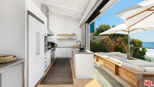a kitchen with stainless steel appliances a sink a stove and a view of living room