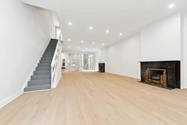a view of an empty room with wooden floor and a fireplace
