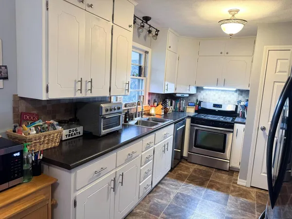 a kitchen with stainless steel appliances granite countertop a stove a sink and a white cabinets