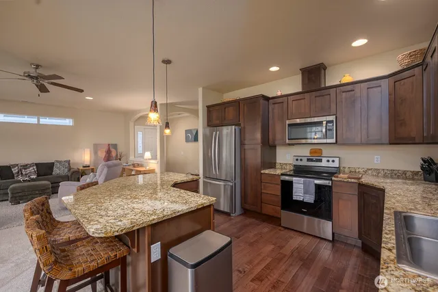 a kitchen with granite countertop kitchen island stainless steel appliances a stove a sink a refrigerator cabinets and dining table