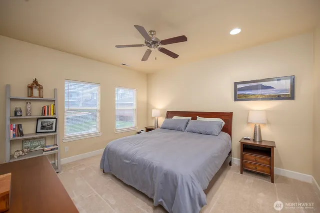 a bedroom with a bed bookshelf and a large window