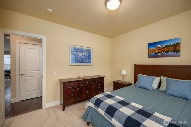 a bedroom with a bed and a lamp on dresser