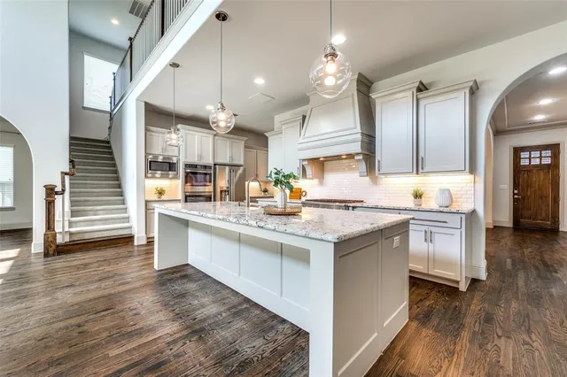 a kitchen with granite countertop a sink cabinets and wooden floor
