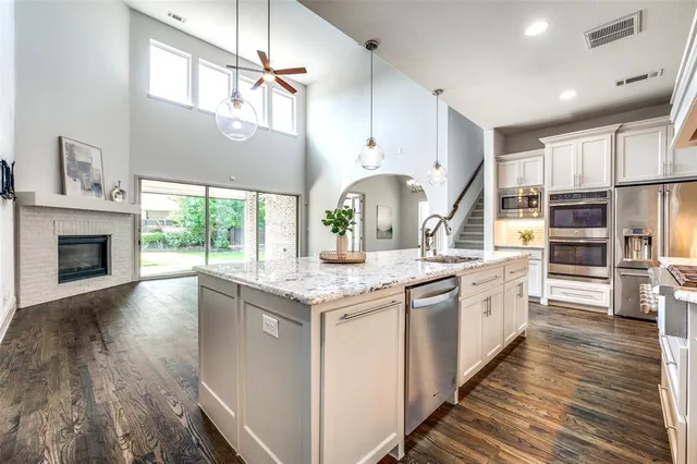 a kitchen with stainless steel appliances granite countertop a lot of counter space and wooden floors