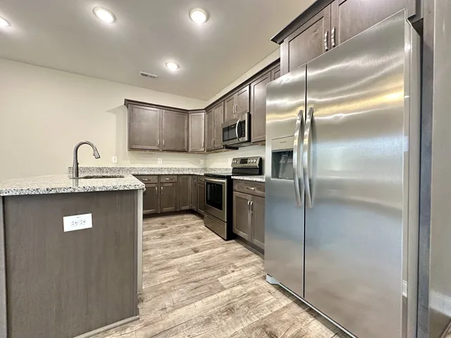 a kitchen with kitchen island a refrigerator and a sink