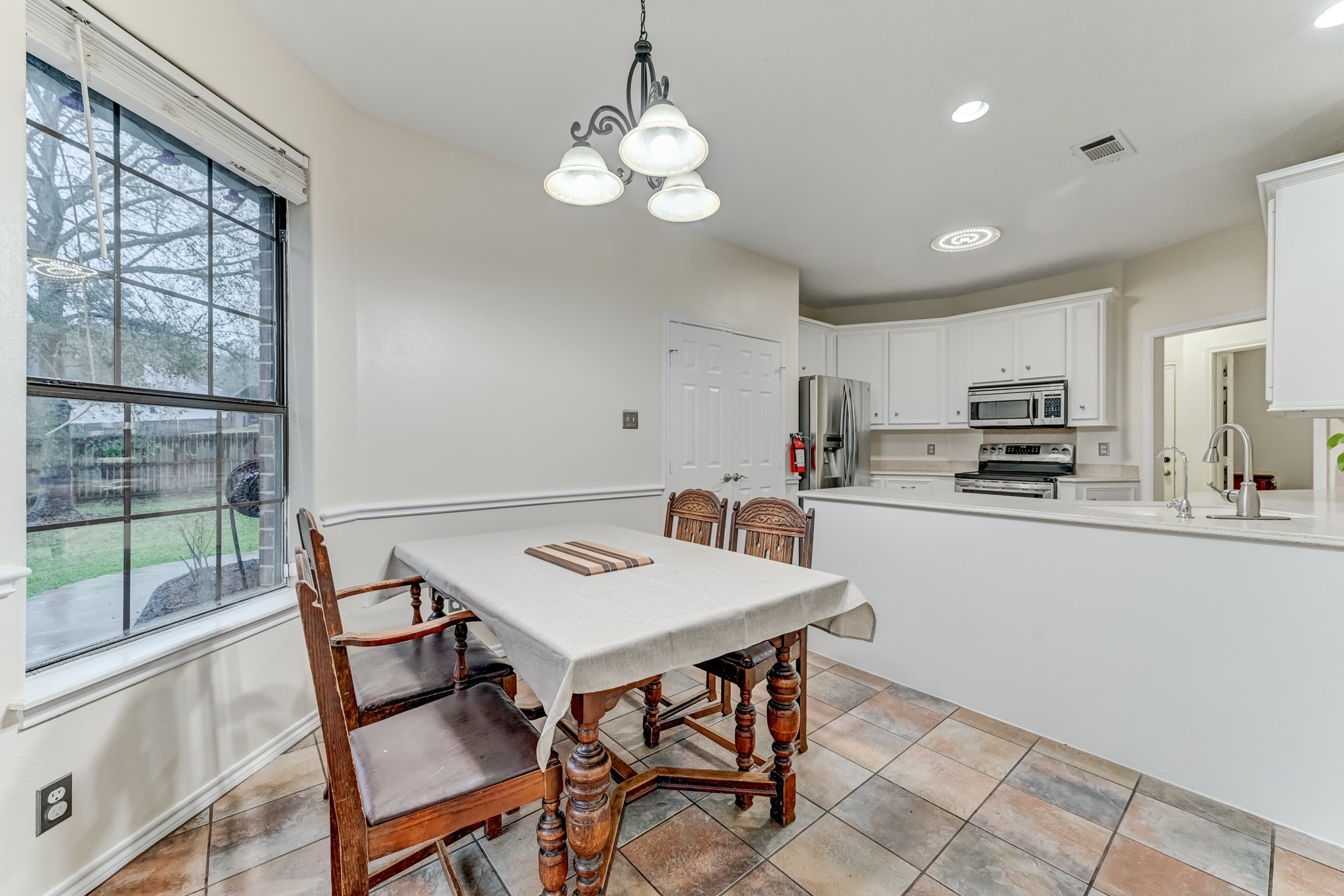 1210 Cherry Creek Road Dayton, TX 77535 - Photo 12 of 50 a kitchen with a table chairs a sink dishwasher window and cabinets