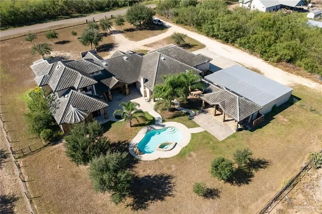 an aerial view of a house with yard and swimming pool