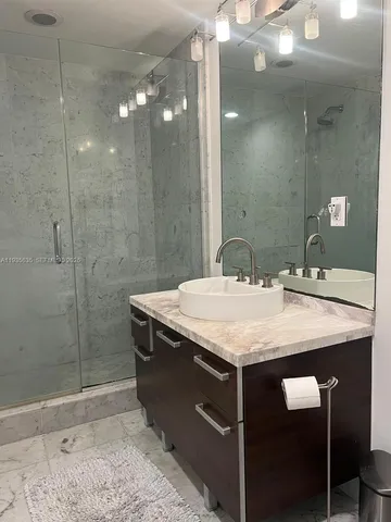 a bathroom with a granite countertop sink a mirror and a shower