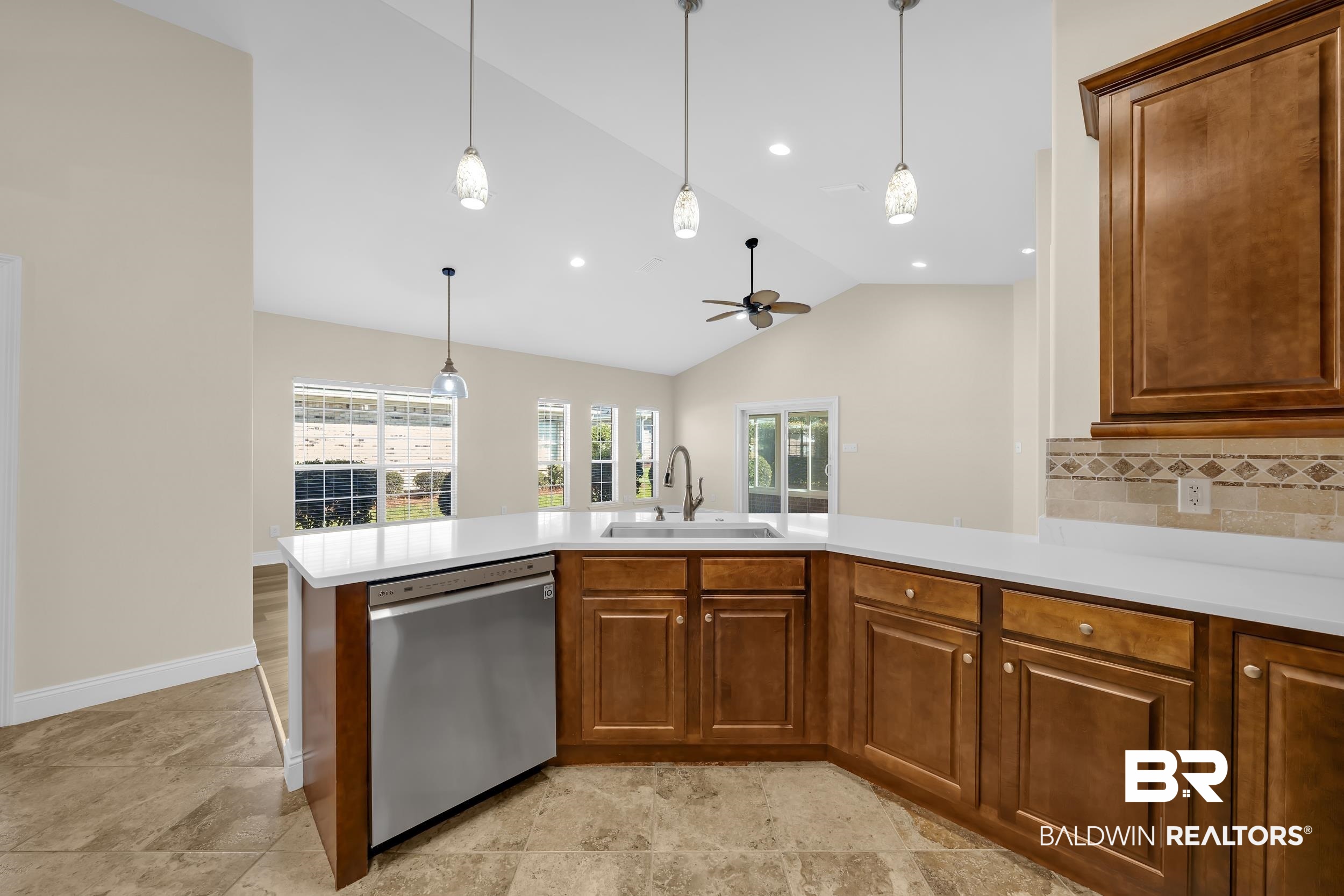 226 Hemingway Loop Foley, AL 36535 - Photo 4 of 53 Kitchen with lofted ceiling, brown cabinets, tasteful backsplash, dishwasher, and hanging light fixtures