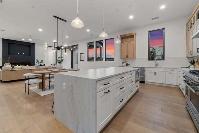 a large kitchen with stainless steel appliances a stove a sink a oven a dining table and chairs