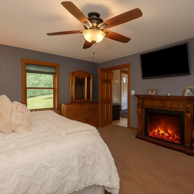 3994 County Rd U South Range, WI 54874 - Photo 21 of 56 Bedroom featuring light carpet, a lit fireplace, and ceiling fan