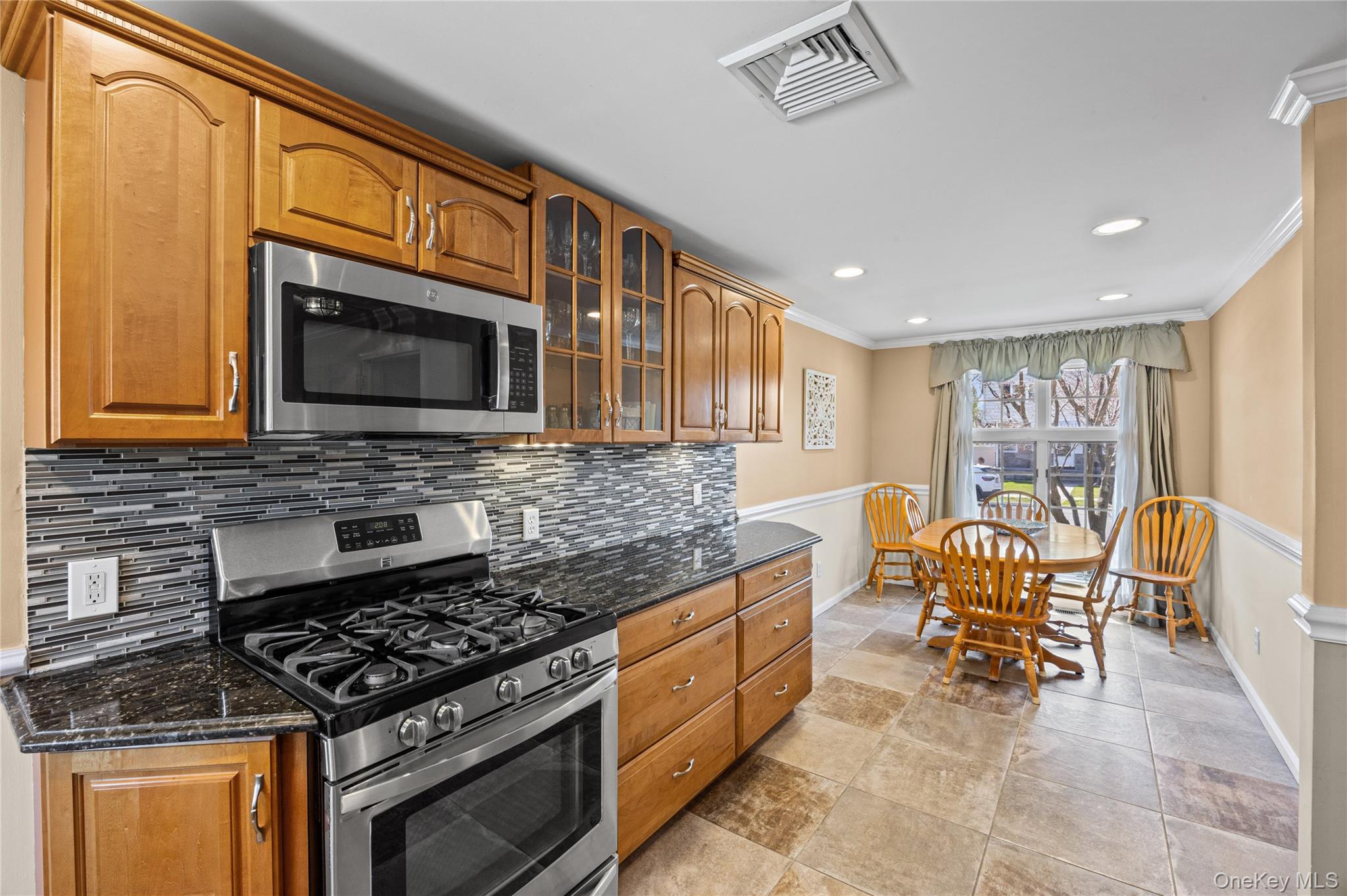 416 Argyle Road Mineola, NY 11501 - Photo 25 of 46 a kitchen with stainless steel appliances granite countertop a stove top oven a sink dishwasher a dining table and chairs with wooden floor