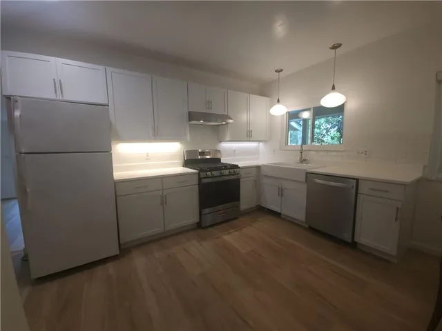 a kitchen with stainless steel appliances granite countertop a sink a stove a refrigerator with wooden floors and cabinets