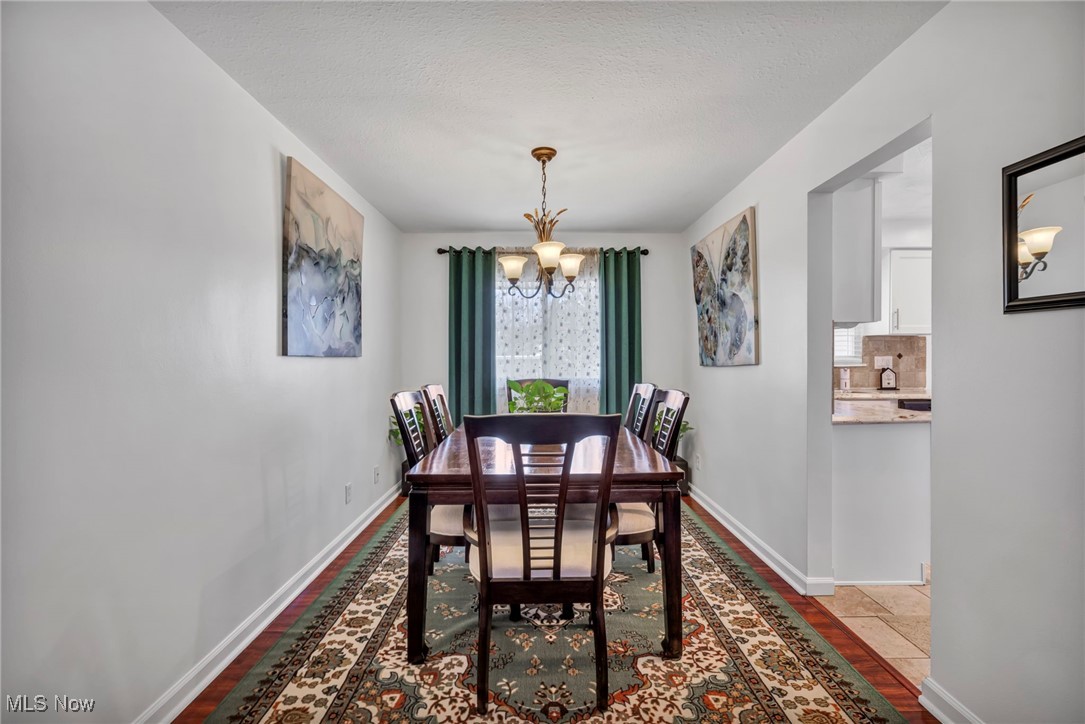 475 Harris Road Cleveland, OH 44143 - Photo 14 of 38 Dining space featuring a textured ceiling, stone tile flooring, baseboards, and a chandelier