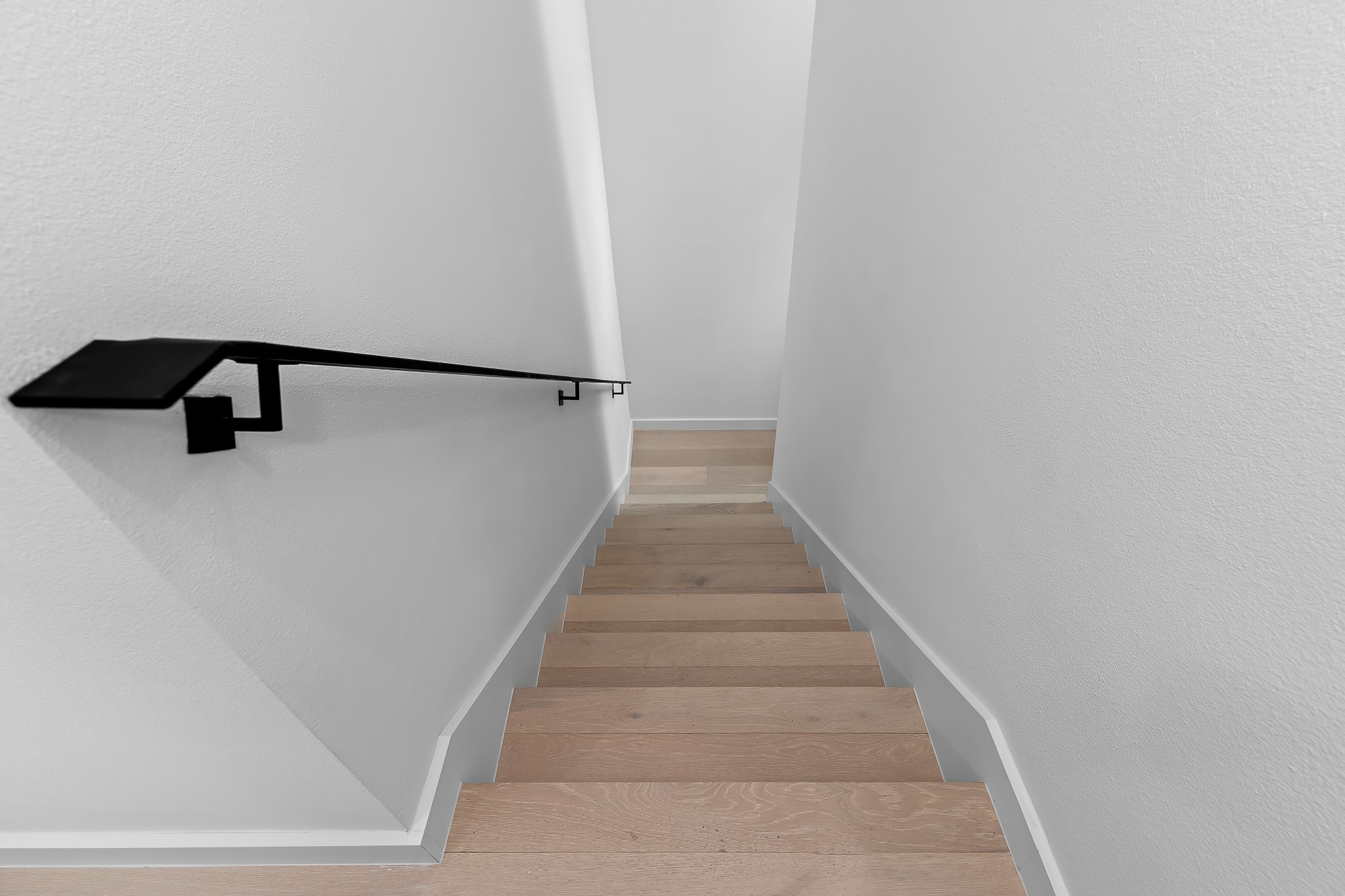 5305 Ledesma Road, Unit 4 Austin, TX 78721 - Photo 22 of 40 Clean lines define this staircase with light wood flooring and a sleek black handrail.